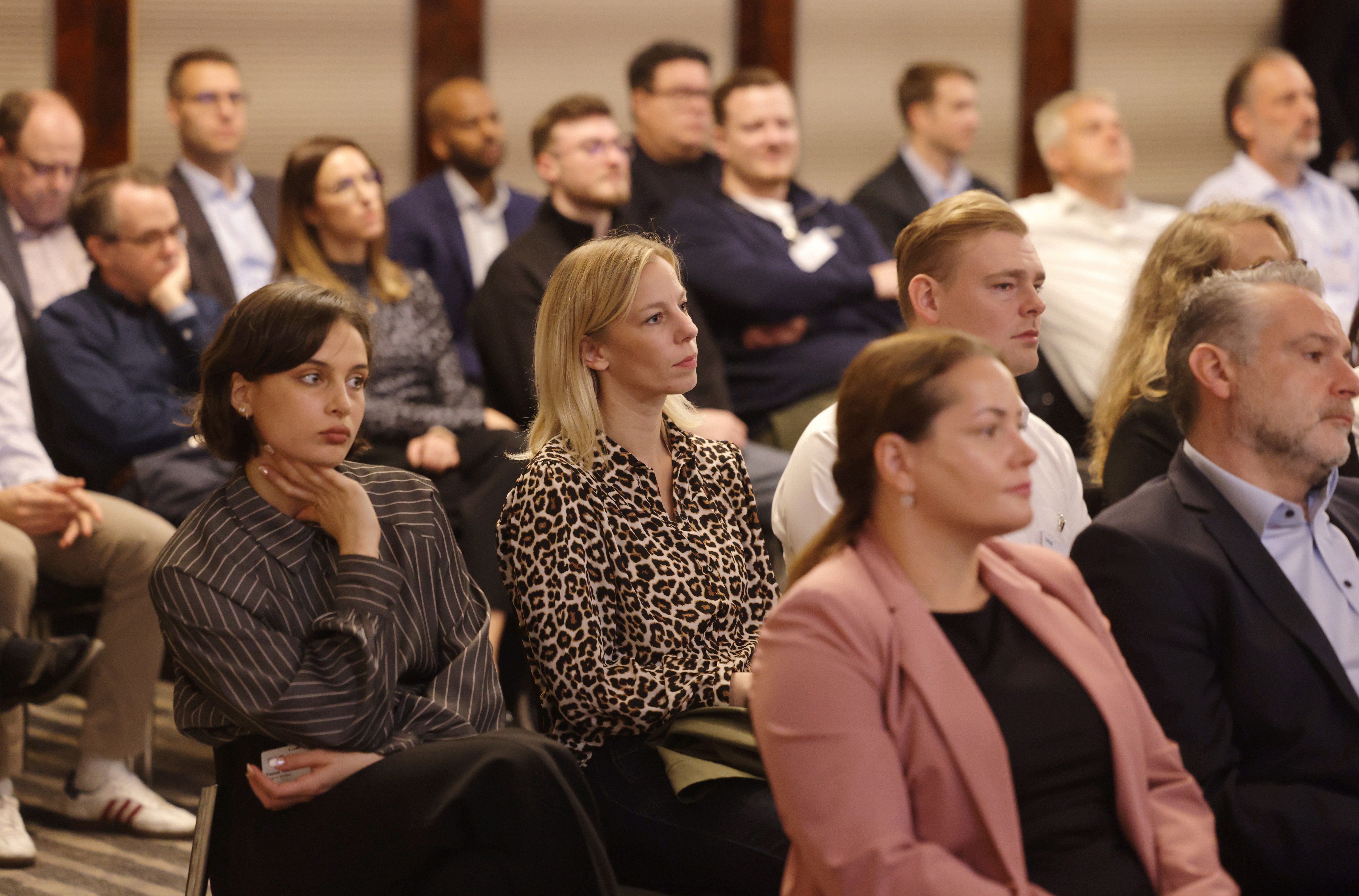 Gruppe von Erwachsenen, die aufmerksam an einer Veranstaltung in einem Raum teilnehmen.