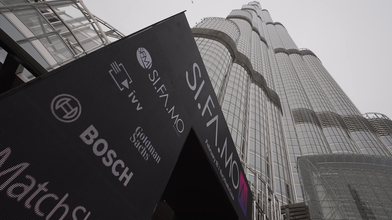 Blick nach oben auf das Burj Khalifa mit einem großen Bildschirm im Vordergrund, der SIFA.MO und verschiedene Sponsorlogos zeigt.